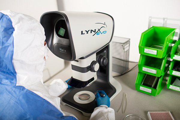 1604-vision-264 but cropped-600×400 Person wearing a hazmat suit in a laboratory using the Lynx EVO stereo microscope