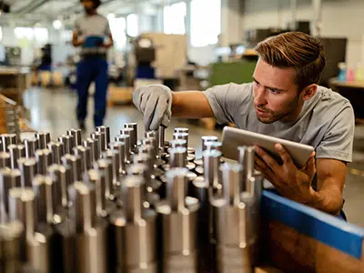 iStock-1152648684-goodsin-400×300 Homme inspectant des pièces métalliques sur une ligne de production